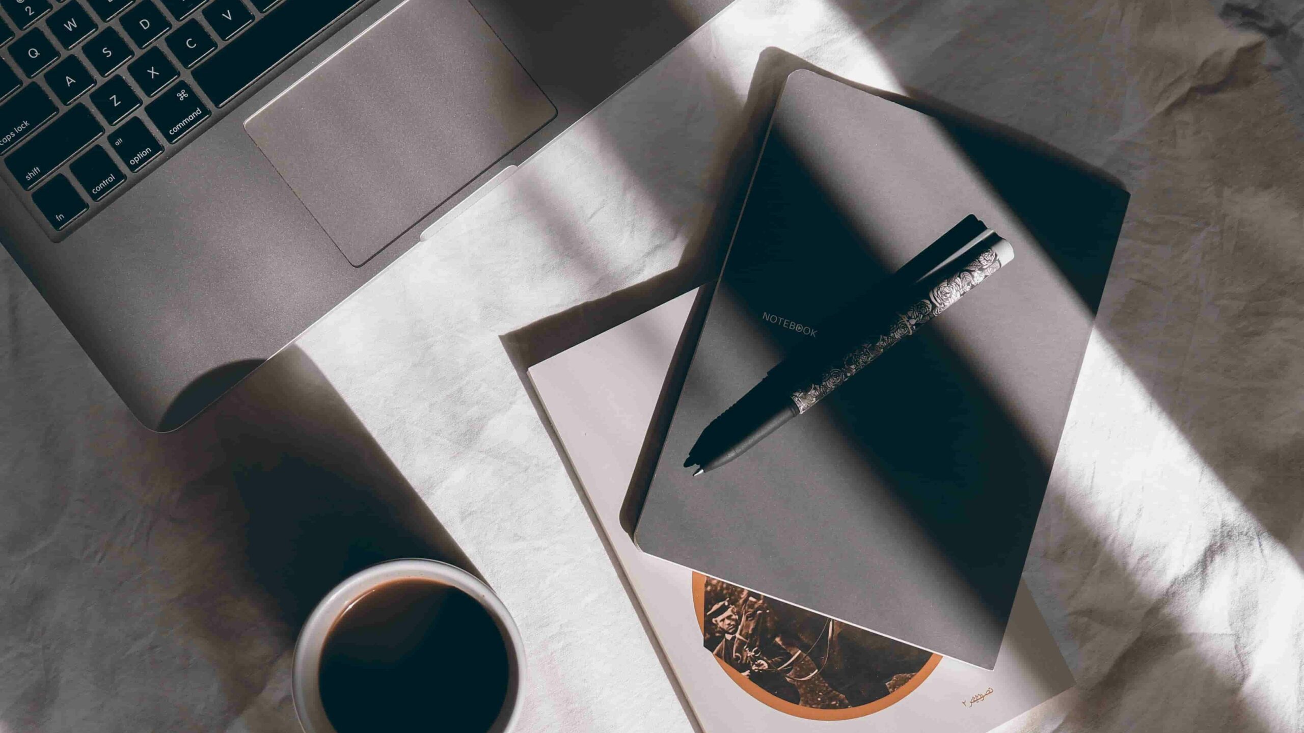 black notebook, black coffee and Macbook